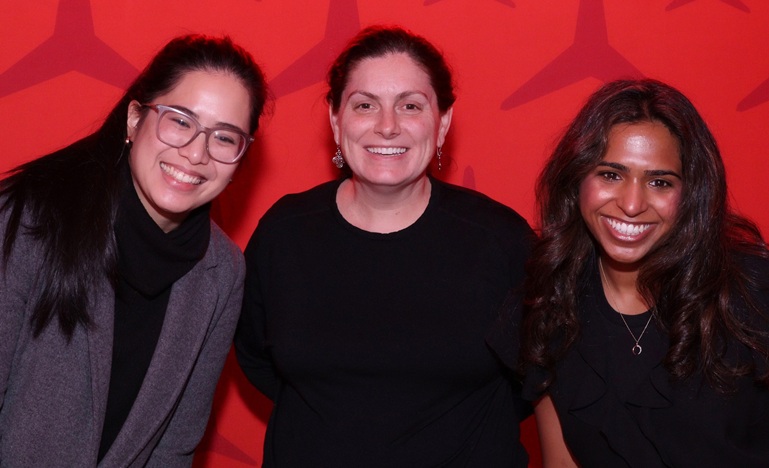 Author Hanaa poses next to her supervisor and a colleague against a red wall featuring the Mercedes-Benz logo and the word Mercedes written above their heads