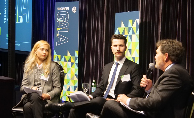 On a stage, with a 'YLD Gala 2025 banner behind them" sit three panelists: Nancy Sarmento Barkhordari at left, Alex Evangelista in the middle, and Chief Justice Wagner at the right, who is speaking