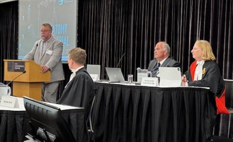 anel discussion at the OBA Conference Centre featuring a speaker at the podium and legal professionals seated at a table with laptops and documents.